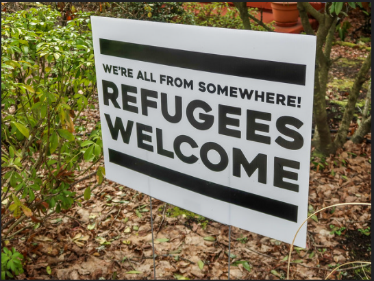 Photo of sign saying "We're all from somewhere! Refugees Welcome"